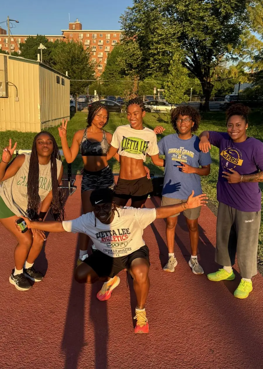Six RepHERsent members posing and smiling on the red track at golden hour